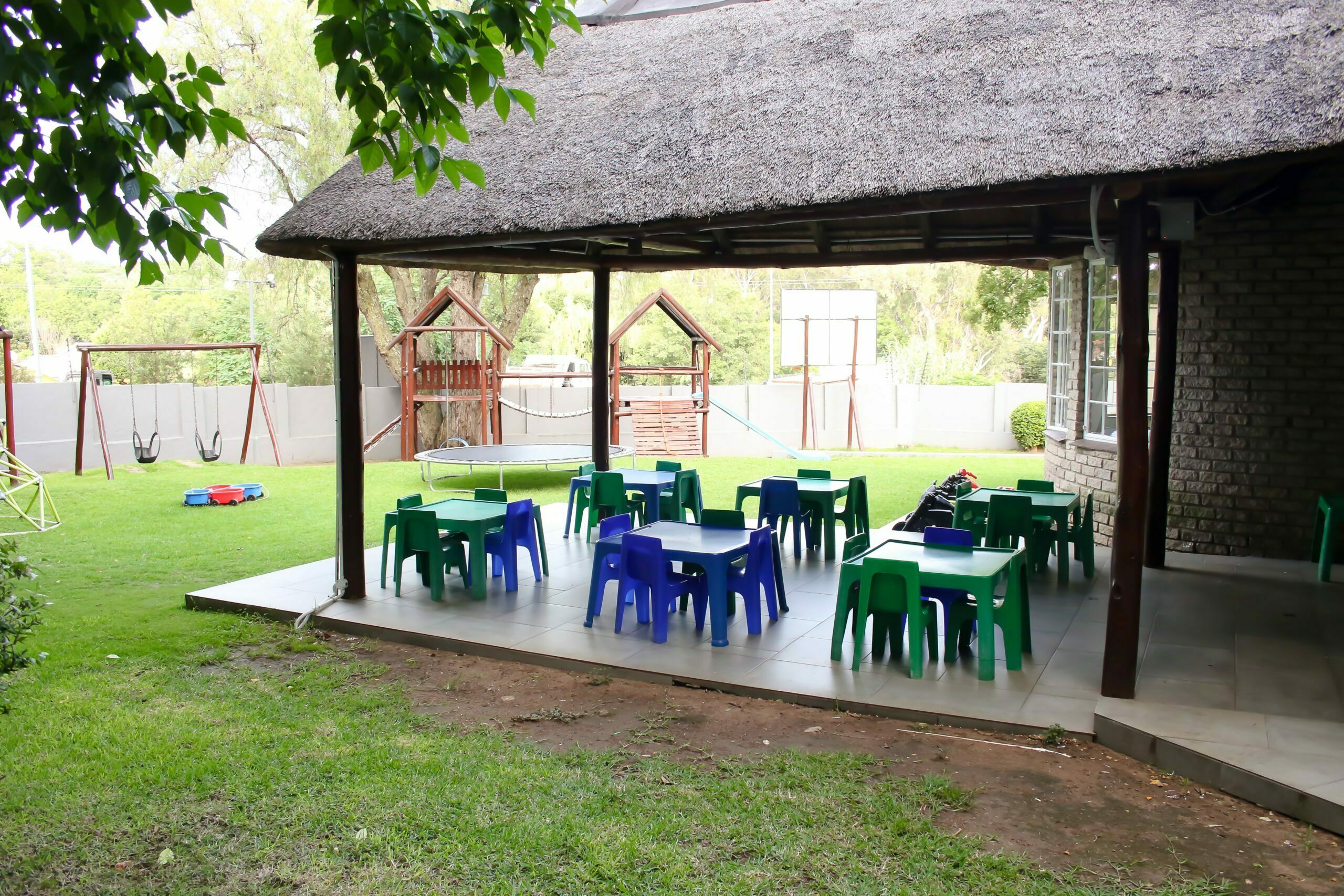 Covered outdoor patio with child-sized tables under a thatched roof