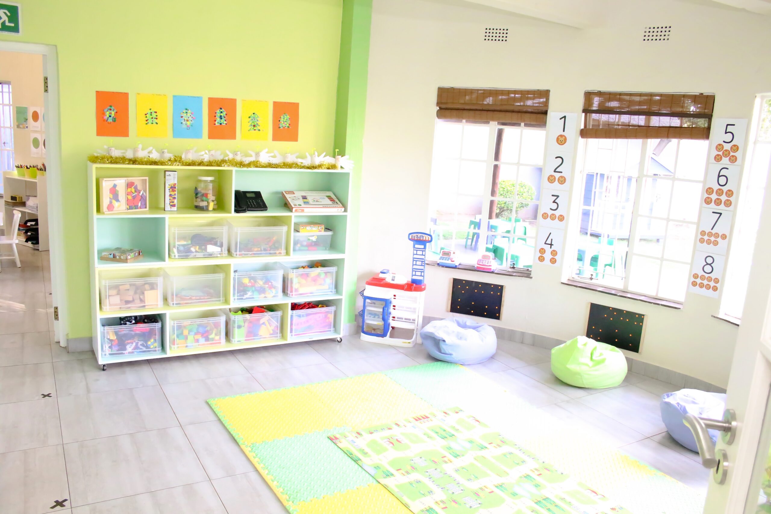 Bright green classroom with toy bins, learning displays and beanbag seating