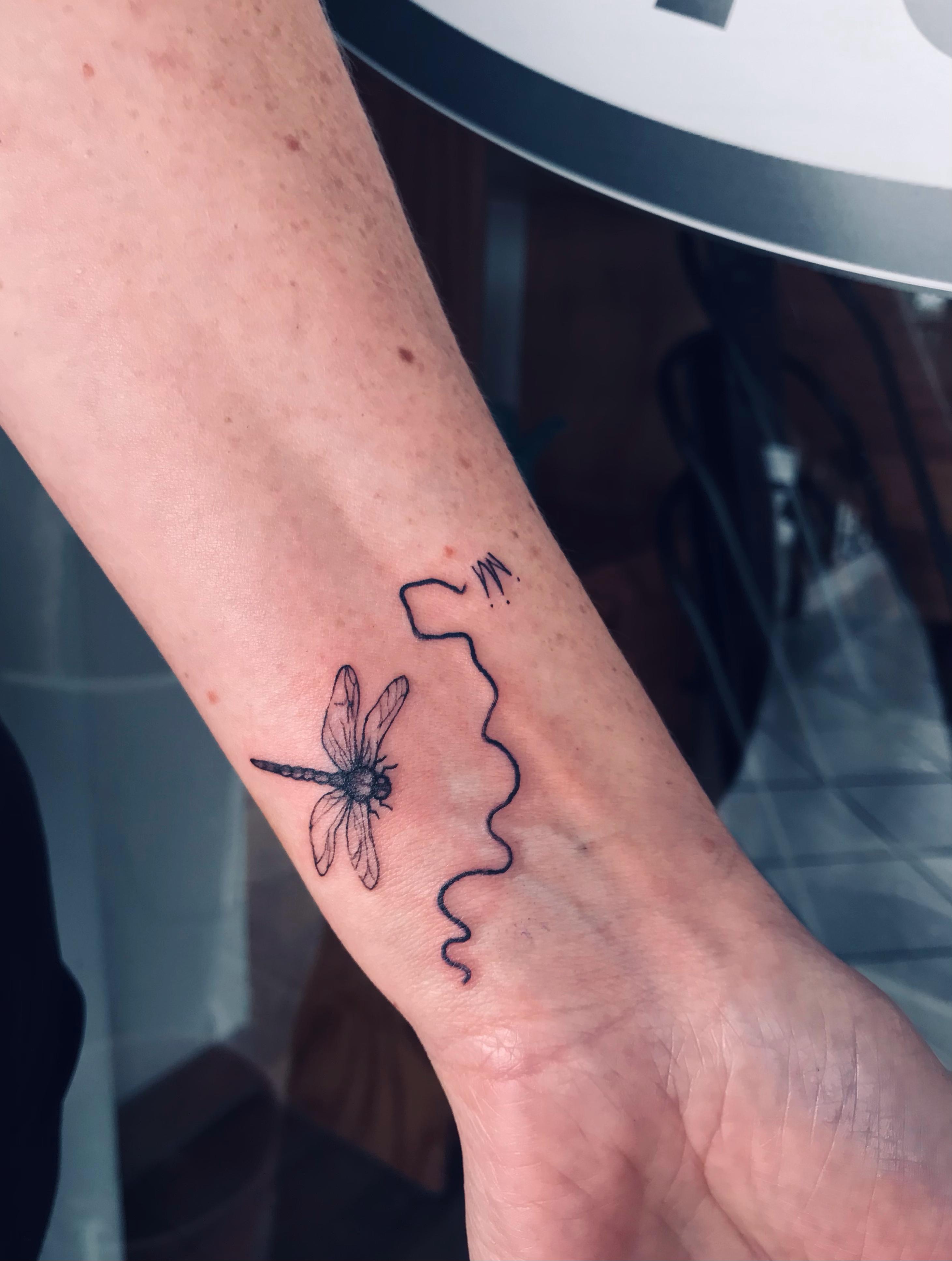 Fine-line dragonfly tattoo on the inner wrist by Ray
