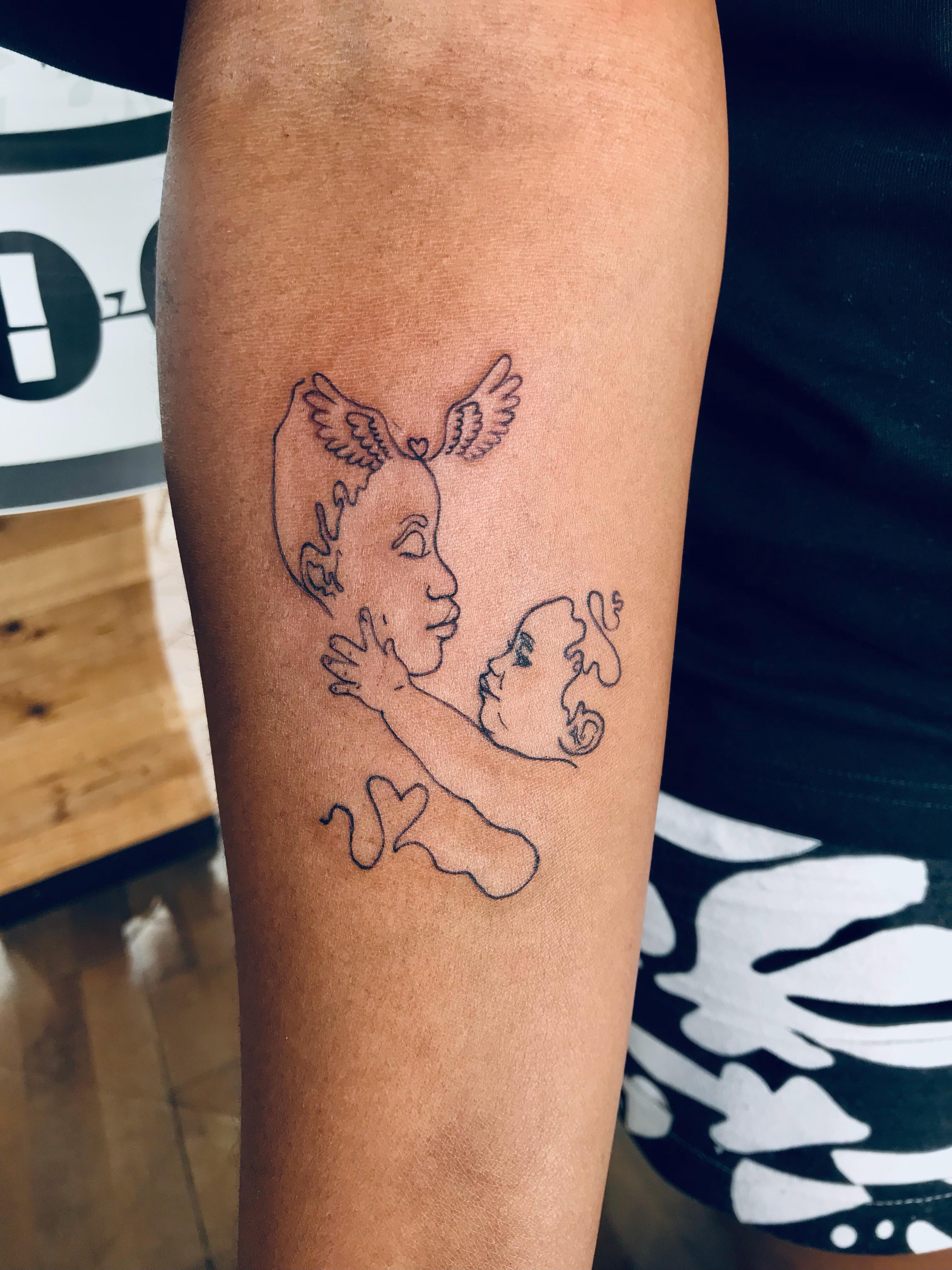 Fine-line mother and cherub tattoo on the forearm by Ray