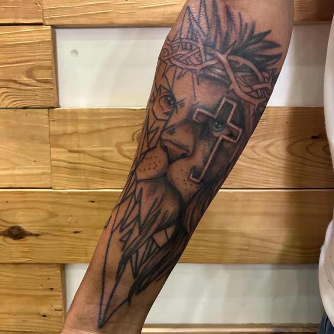 Black-and-grey lion and cross tattoo on the forearm by Rob