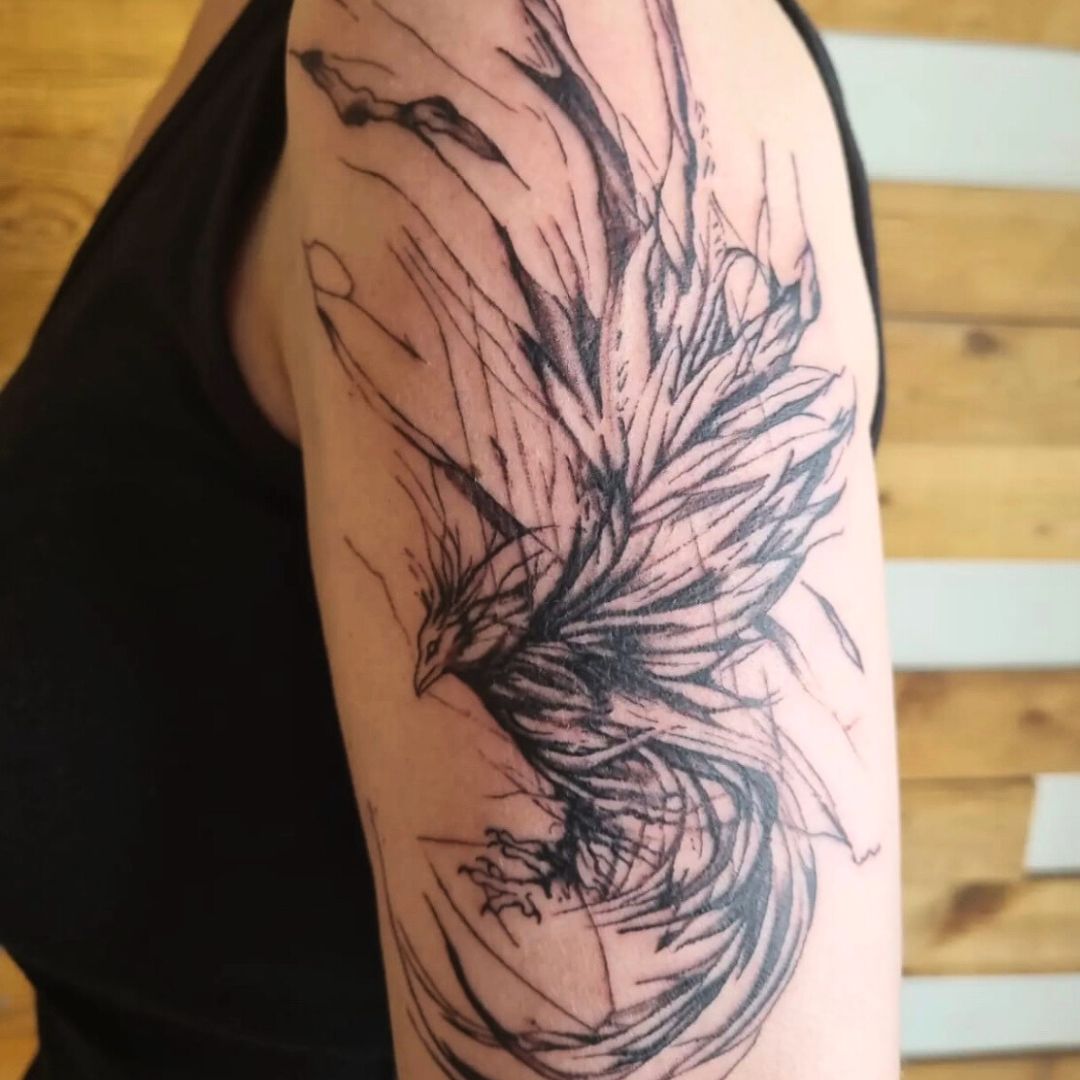 Sketch-style black-and-grey phoenix tattoo on the upper arm by Rob