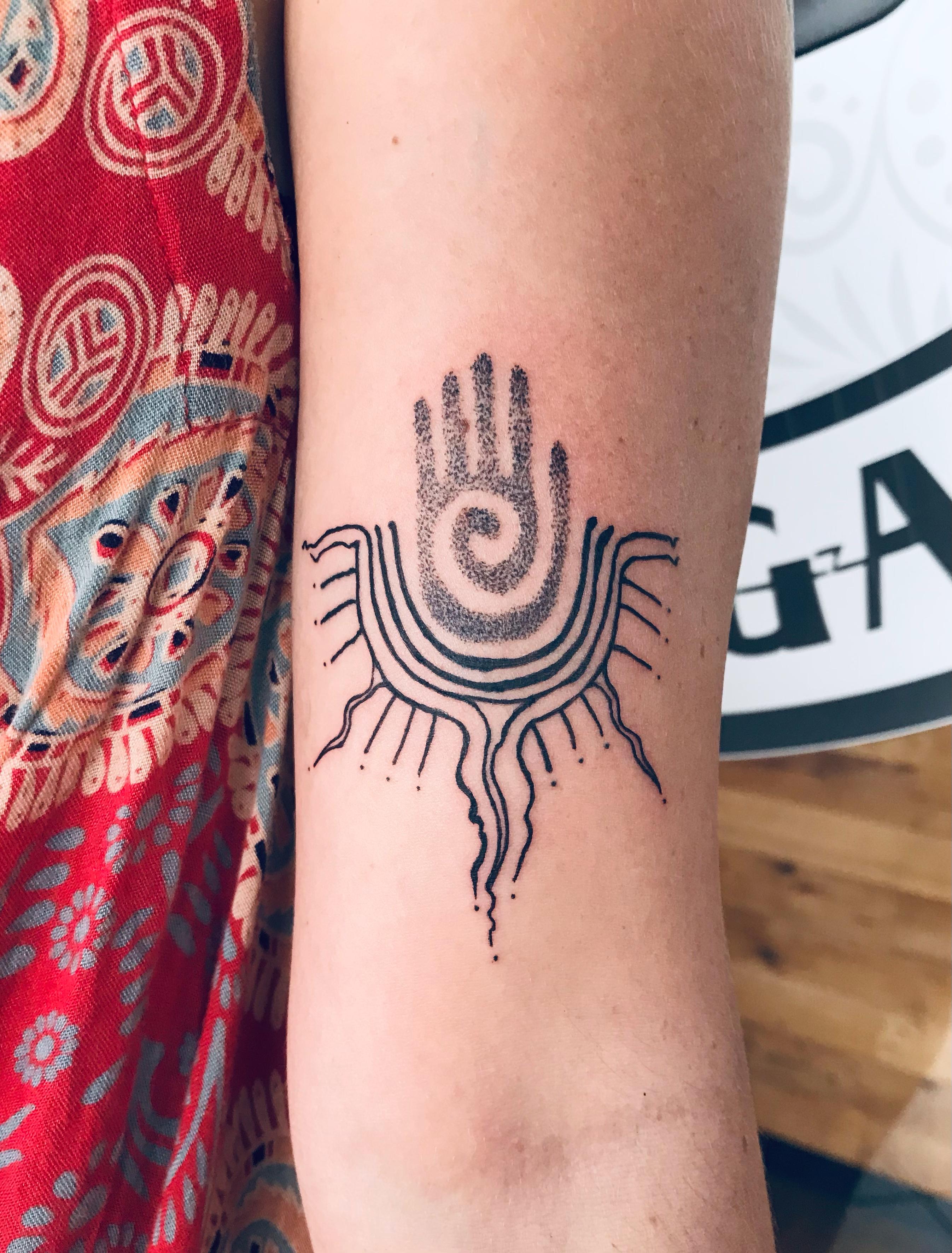 Tribal dot-work hand symbol tattoo on the forearm by Ray