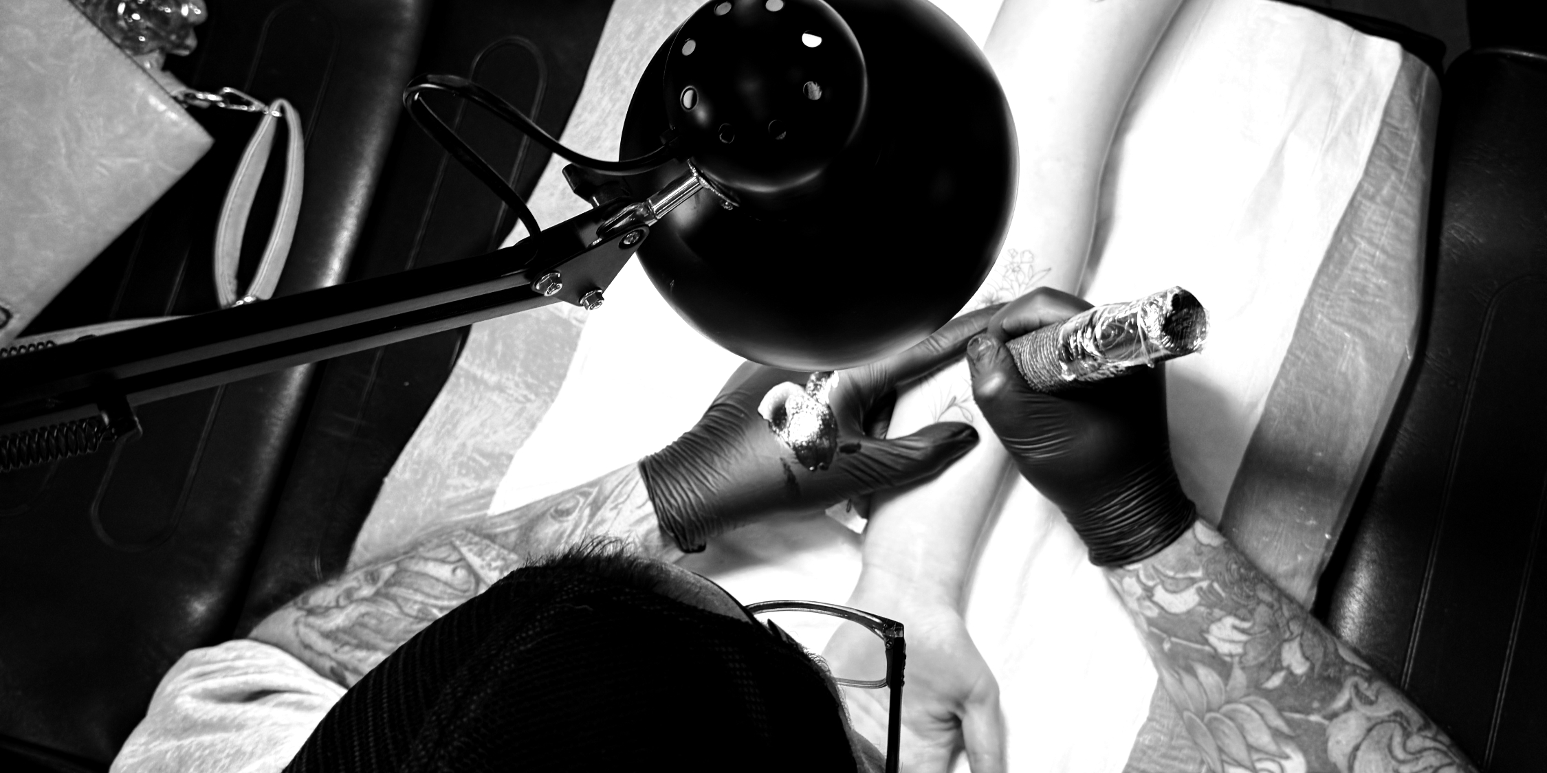Tattoo artist at work under the studio lamp at The Tattoo Gallery